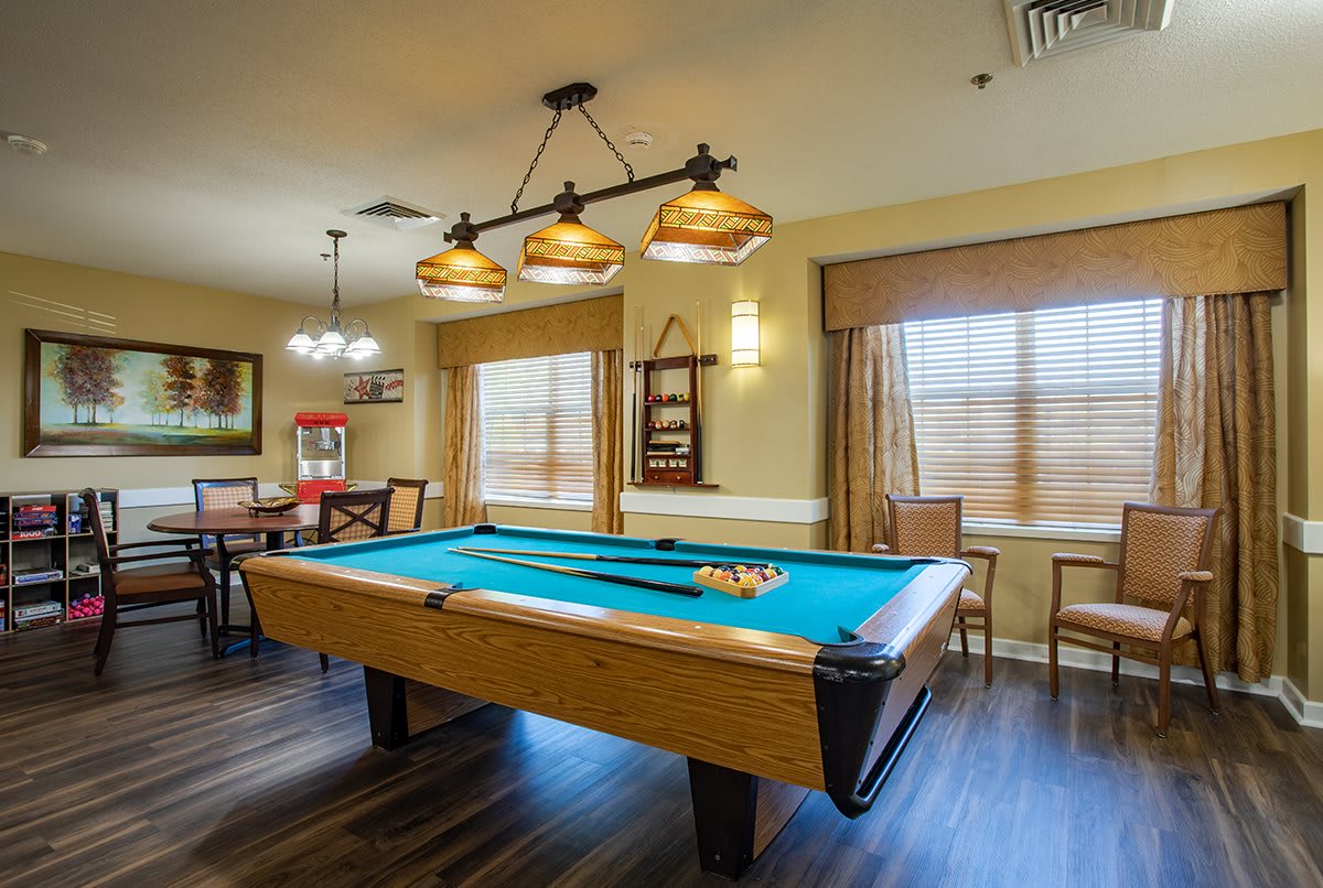 A cozy game room featuring a pool table with overhead lighting and wooden furnishings.