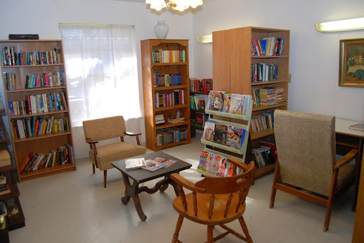 A cozy reading area featuring wooden bookshelves filled with books, comfortable seating, and a warm atmosphere.