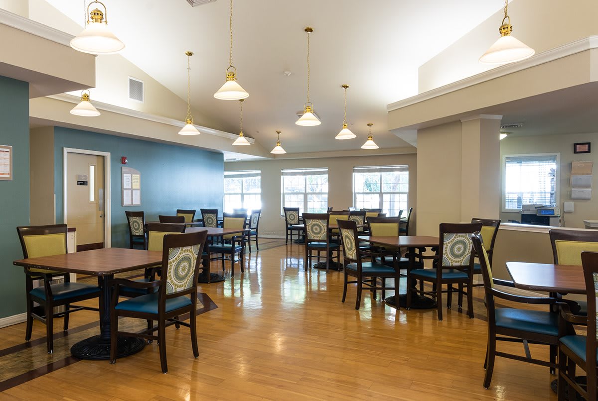 A spacious and well-lit dining room with multiple tables and chairs arranged neatly.