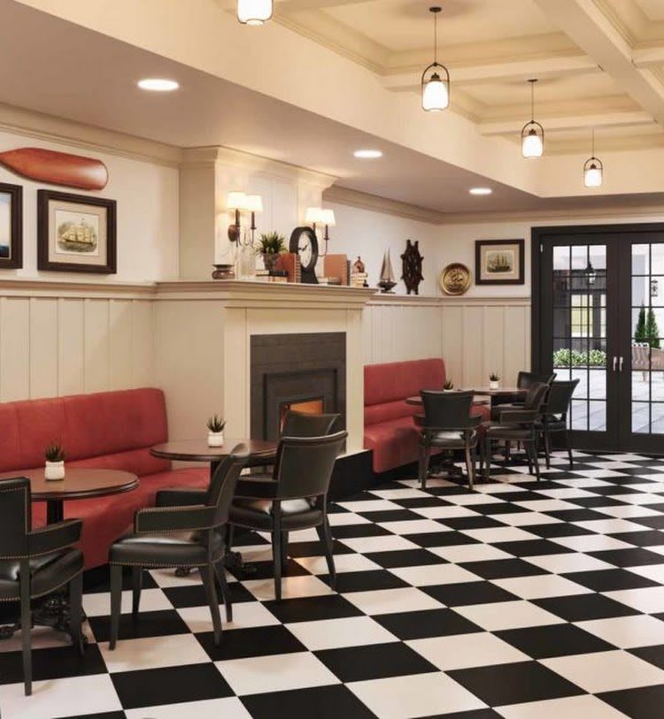A cozy cafe interior with red seating, checkerboard flooring, and decorative wall art.