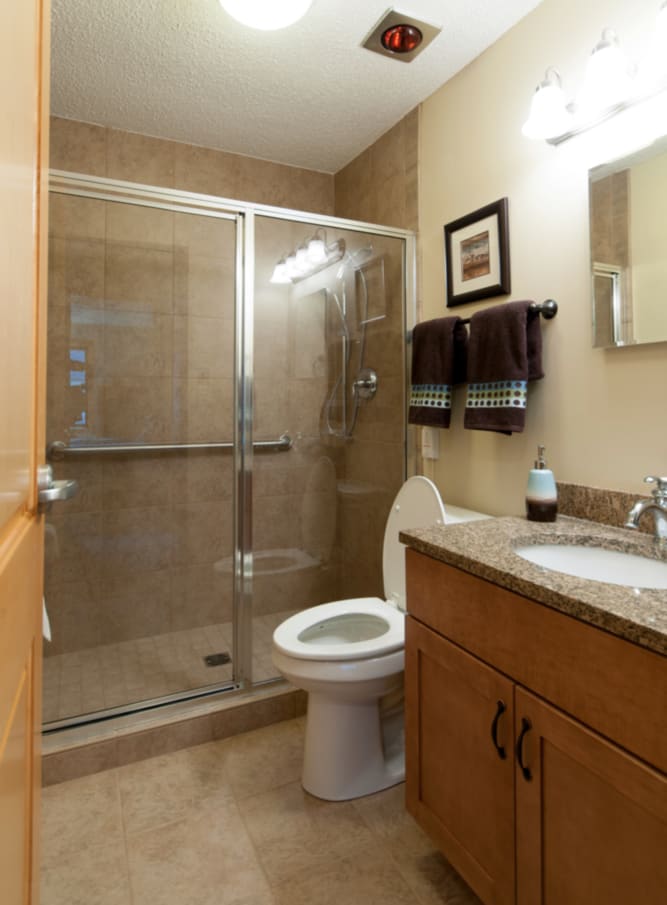A modern bathroom with a glass-enclosed shower, toilet, and sink.