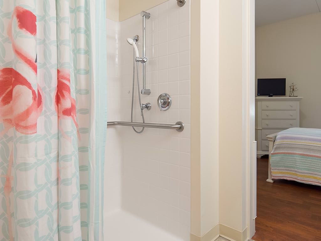 A modern bathroom featuring a shower with a grab bar and a colorful curtain.