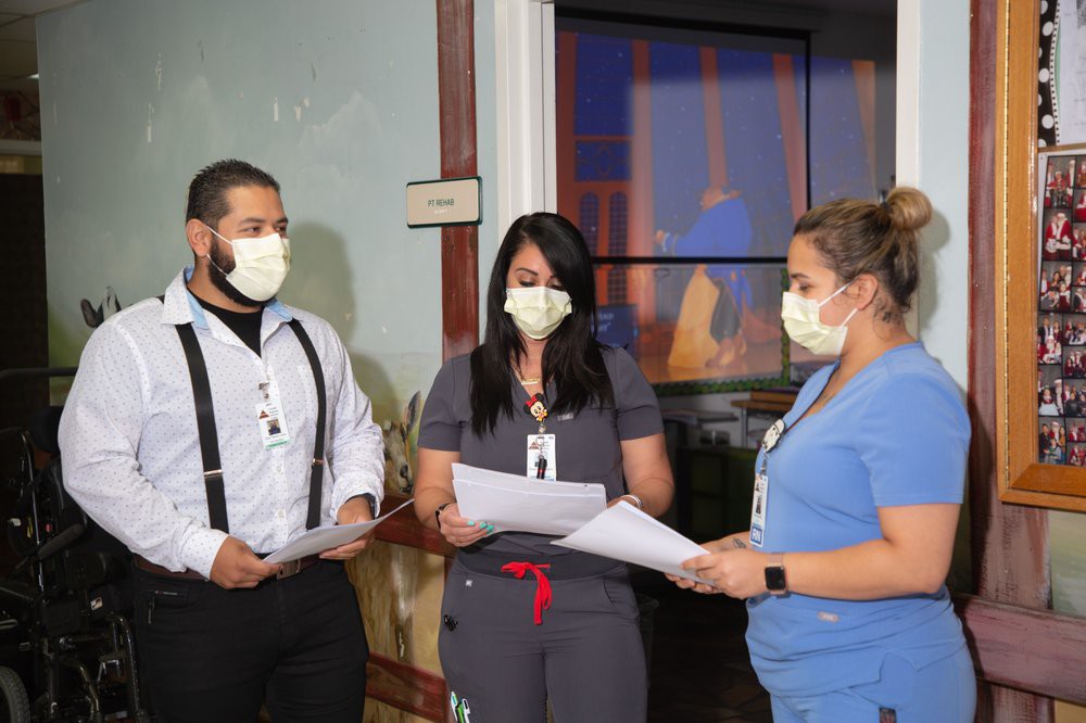 Healthcare professionals in a hospital setting discussing patient care while wearing masks.