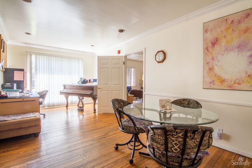 A cozy dining area with a glass table, chairs, and a piano in the background.
