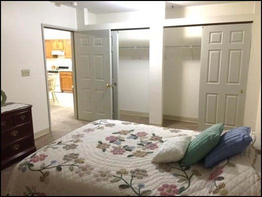A cozy bedroom featuring a floral bedspread and multiple closet doors.