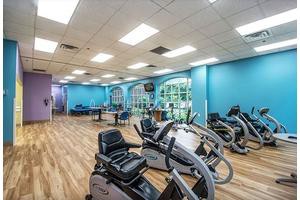 A spacious and well-lit gym with exercise bikes and various fitness equipment.