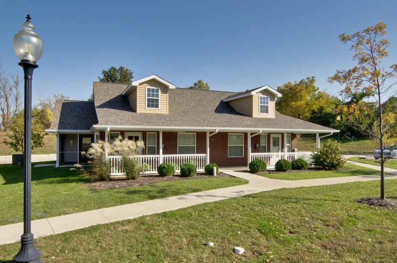 A suburban house with a large porch and well-maintained lawn.