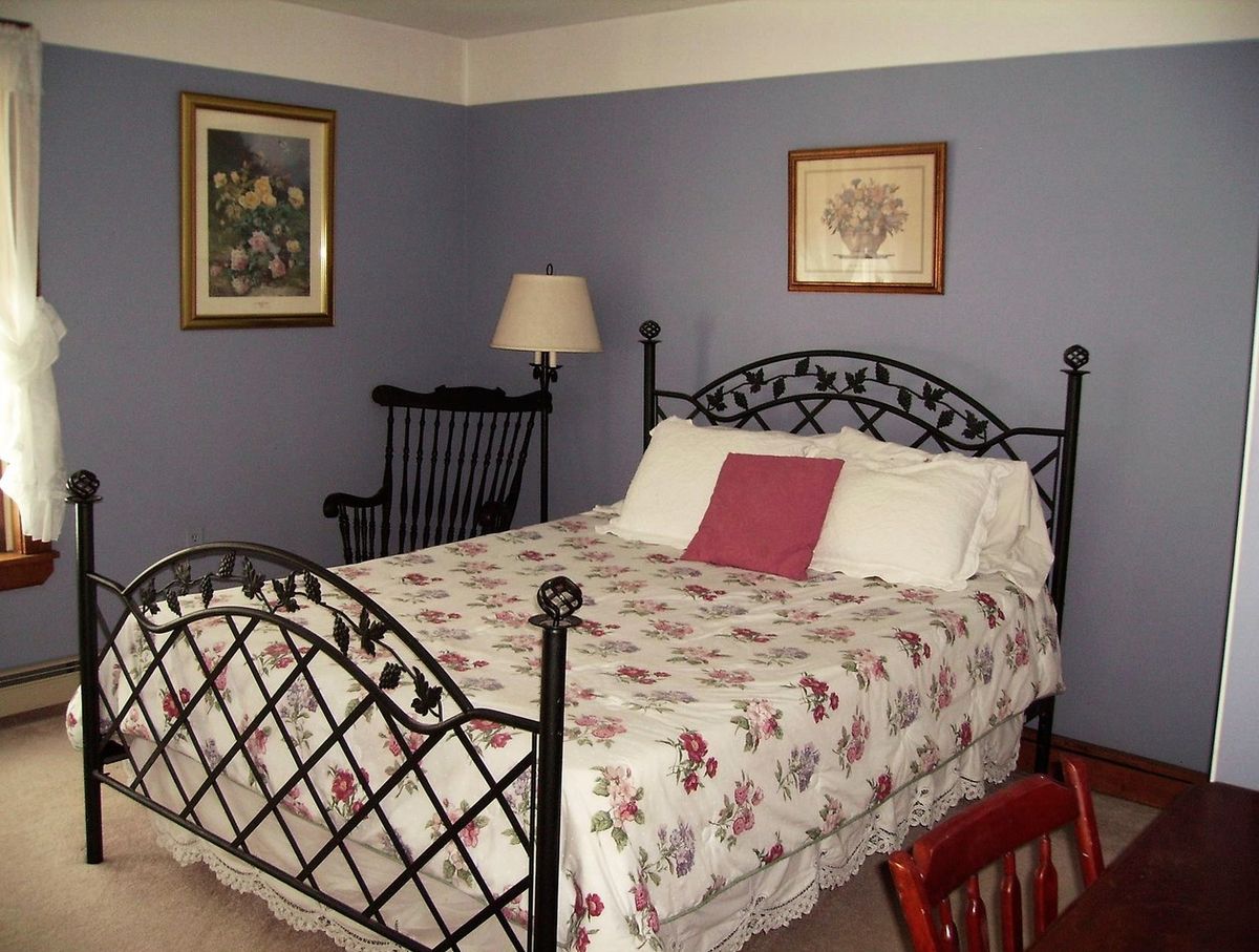 A cozy bedroom with a floral-patterned bed, metal frame, and decorative wall art.