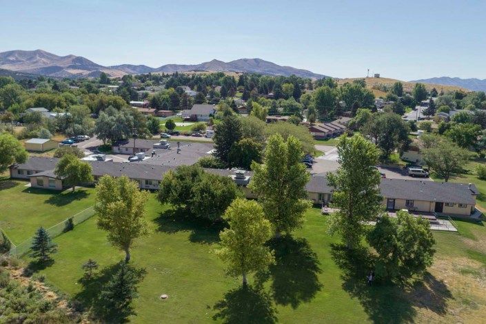 An aerial view of a suburban area with lush greenery and surrounding hills.