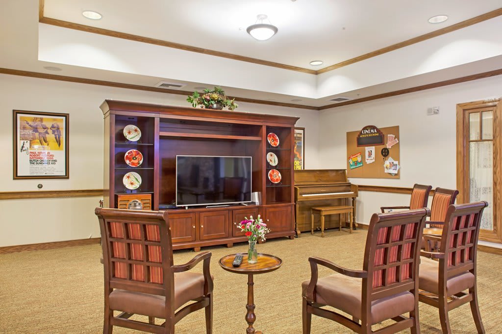 Cozy living room with a television, chairs, and a piano.