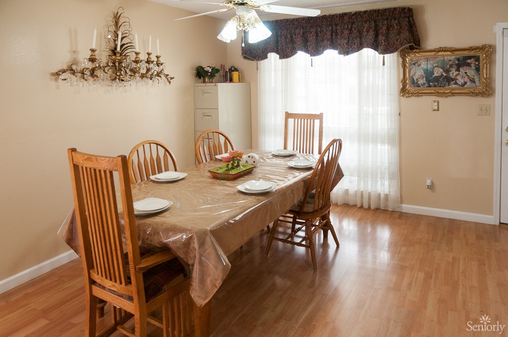 A cozy dining room with a table set for four, featuring wooden chairs and a chandelier.