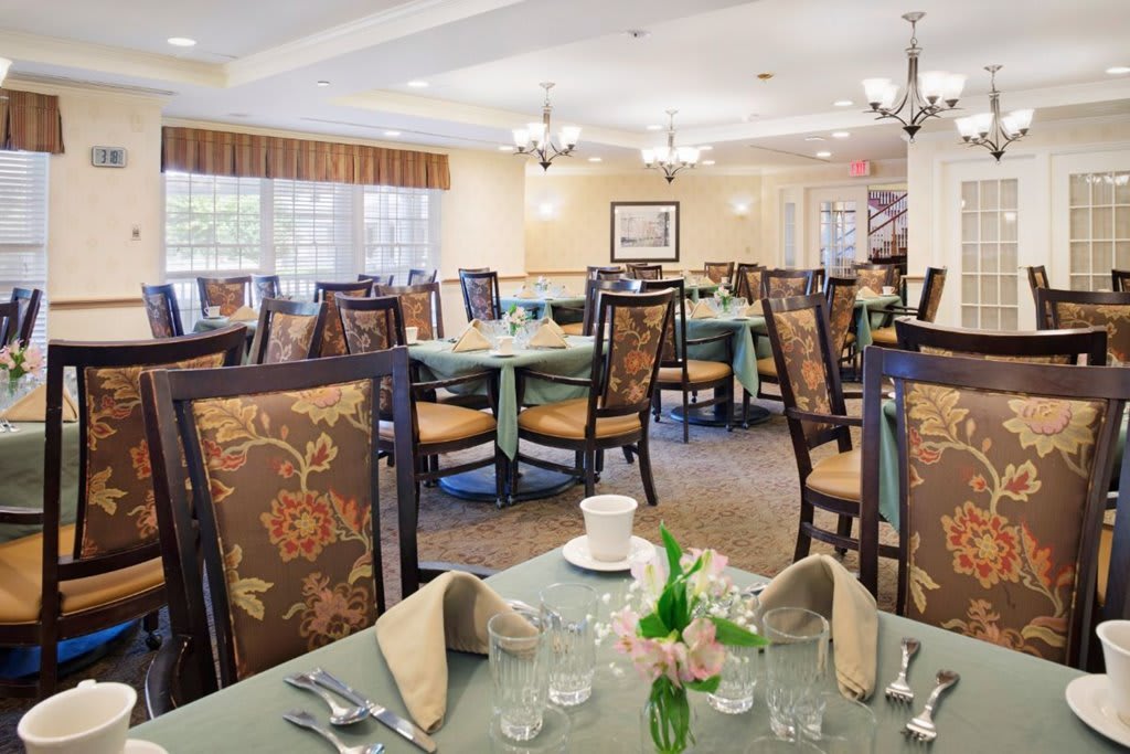 A spacious dining room with elegantly set tables and upholstered chairs.