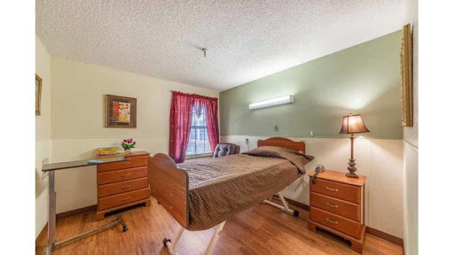 A cozy hospital bedroom featuring a bed, nightstands, and warm lighting.