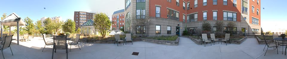 Outdoor view of an urban building with chairs and a tree.