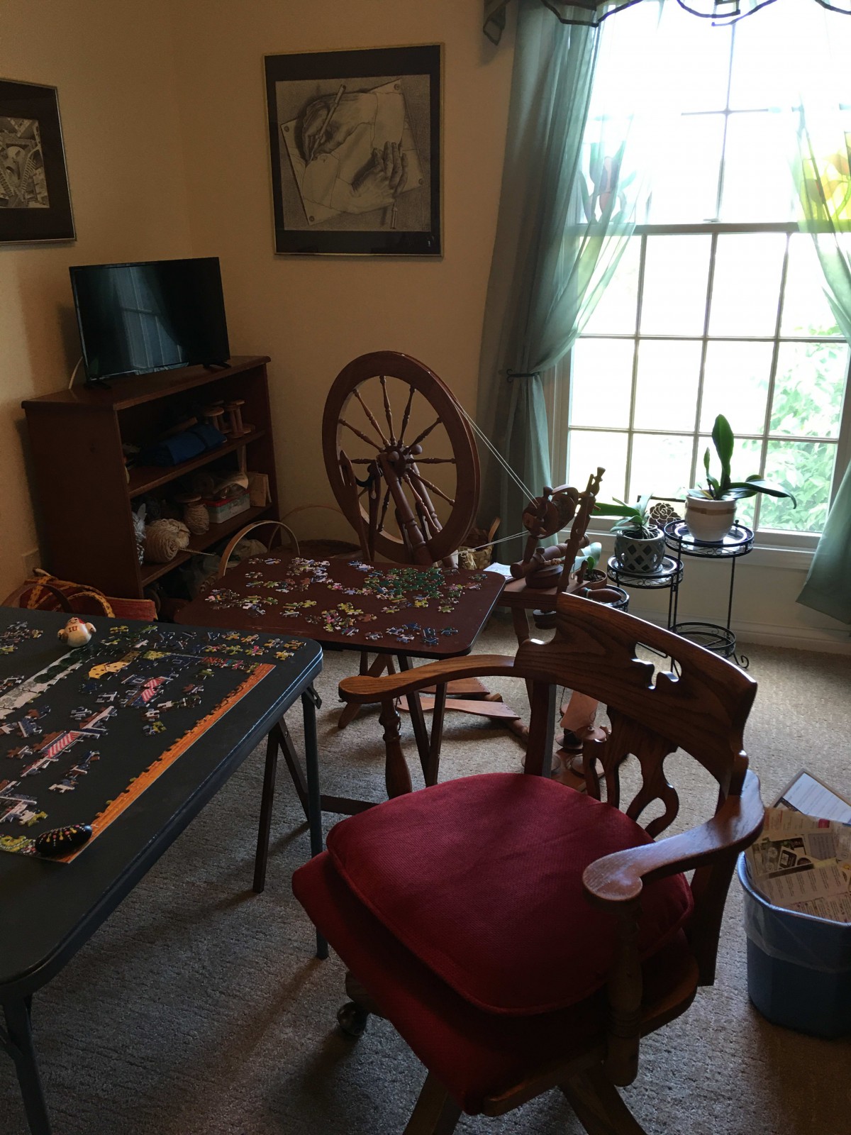 A cozy room with a puzzle in progress and a spinning wheel near the window.