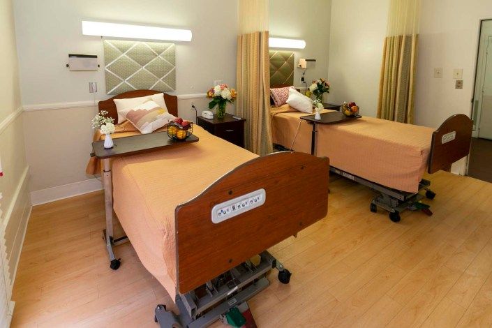 A hospital room with two patient beds, each adorned with flowers and pillows.