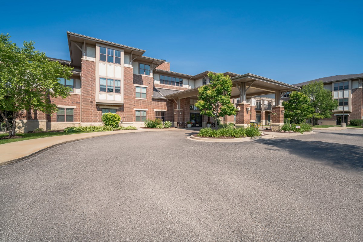 A modern residential apartment complex with a landscaped entrance and clear blue sky.