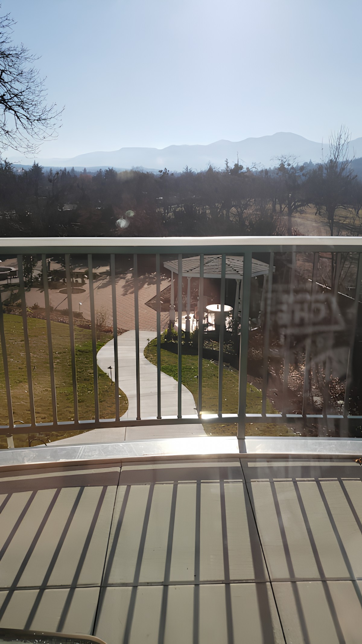 View from a balcony overlooking a winding pathway and trees.