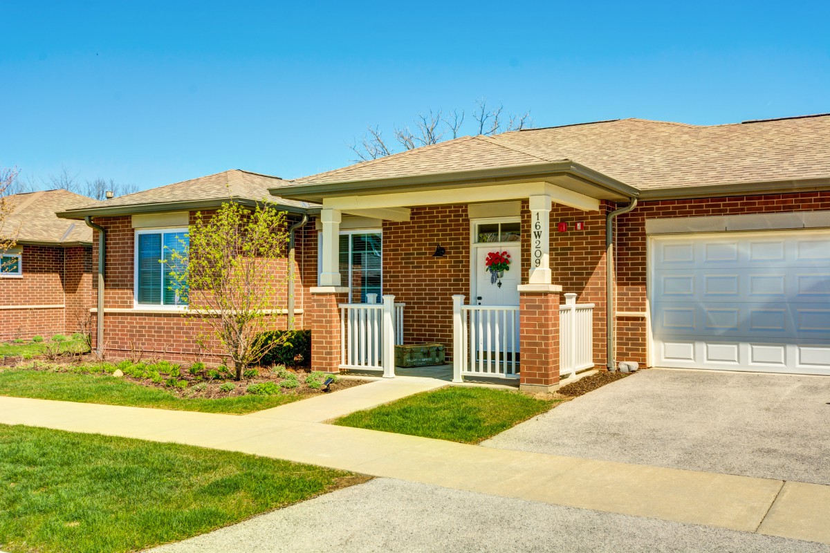 A charming brick bungalow with a tidy front yard and driveway.
