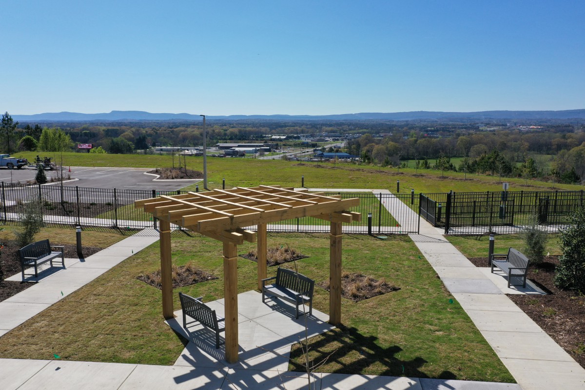 A pergola with benches in a scenic outdoor setting on a sunny day.