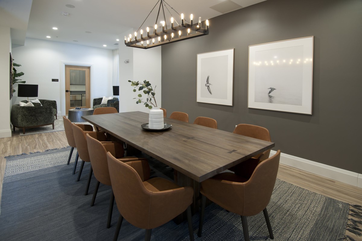 A modern dining room with a large wooden table, stylish chairs, and an elegant chandelier.