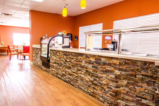 A modern cafe interior featuring a stone counter and vibrant orange walls.