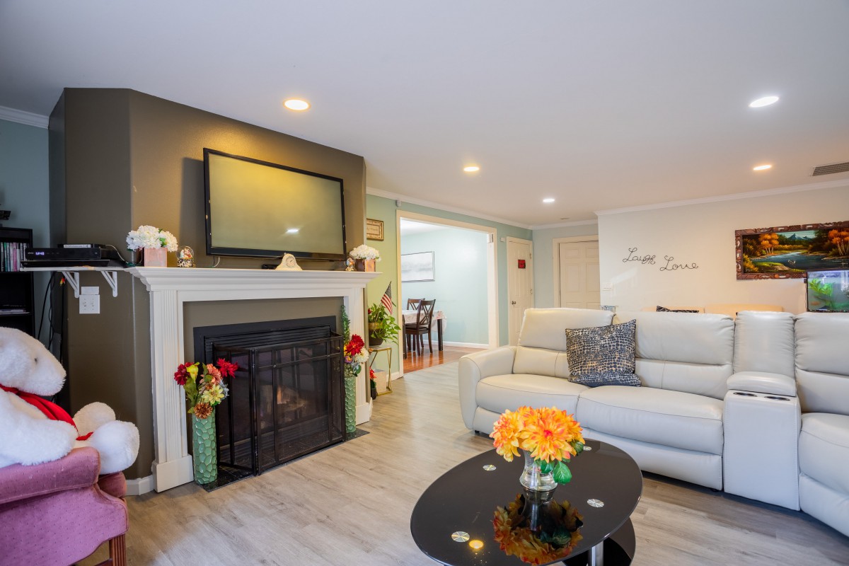 A modern living room featuring a cozy fireplace, a large sofa, and a sleek coffee table adorned with flowers.