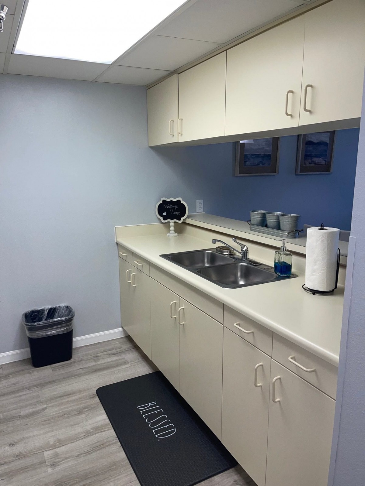 A small office kitchenette with a sink, cabinets, and paper towels.