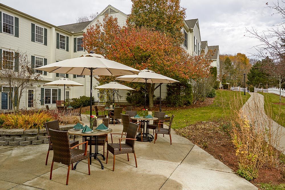 Outdoor patio with tables and chairs under umbrellas, surrounded by autumn foliage.