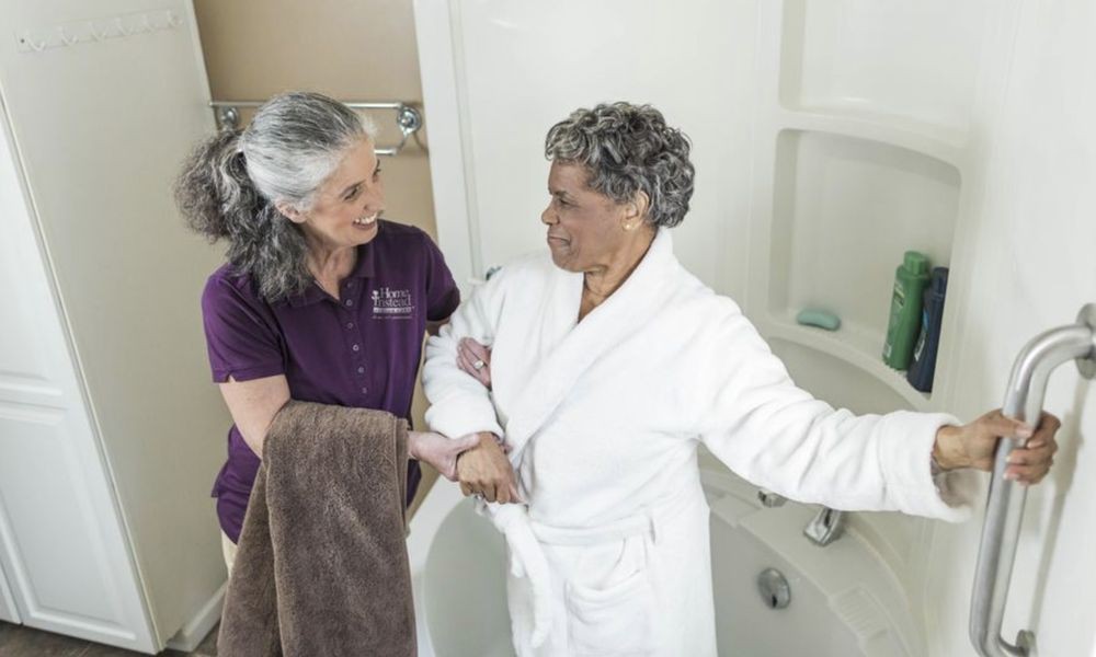 A caregiver assisting an elderly person in the bathroom.
