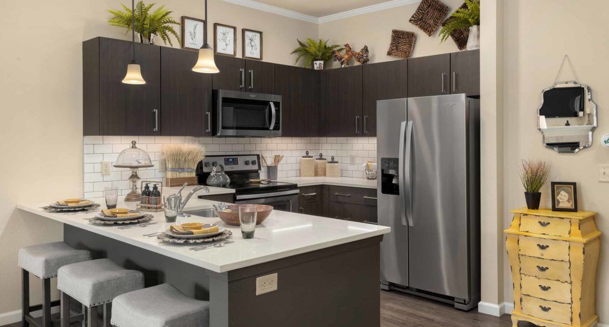 A modern kitchen with dark cabinets, stainless steel appliances, and a central island.