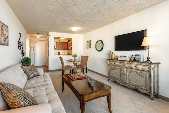 A cozy living room with a sofa, dining area, and wall-mounted TV.