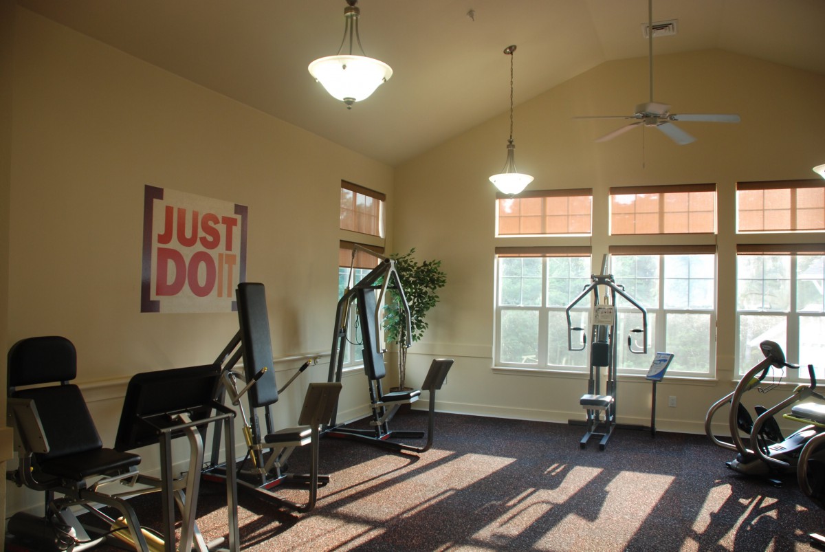 A well-lit gym with various fitness equipment and a motivational poster on the wall.