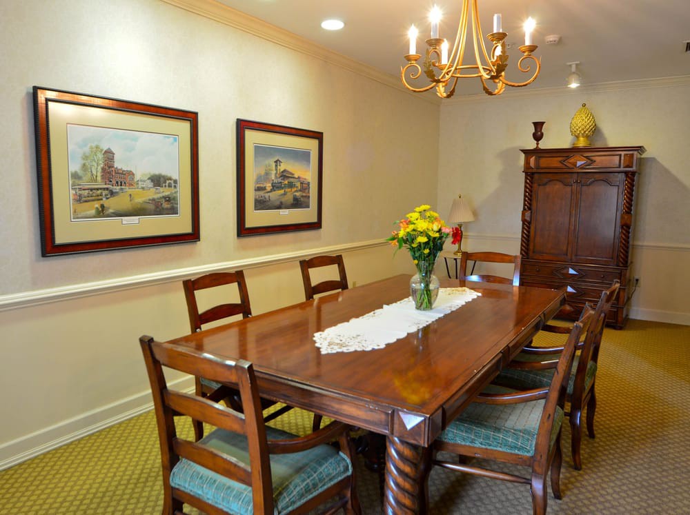 A cozy dining room featuring a wooden table with chairs, a chandelier, and artwork on the walls.