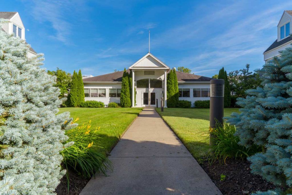 A beautiful building with a pathway leading through a lush lawn and landscaped garden.