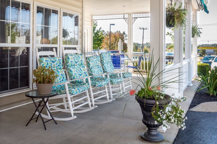 A cozy porch featuring patterned rocking chairs and potted plants, offering a relaxing outdoor seating area.
