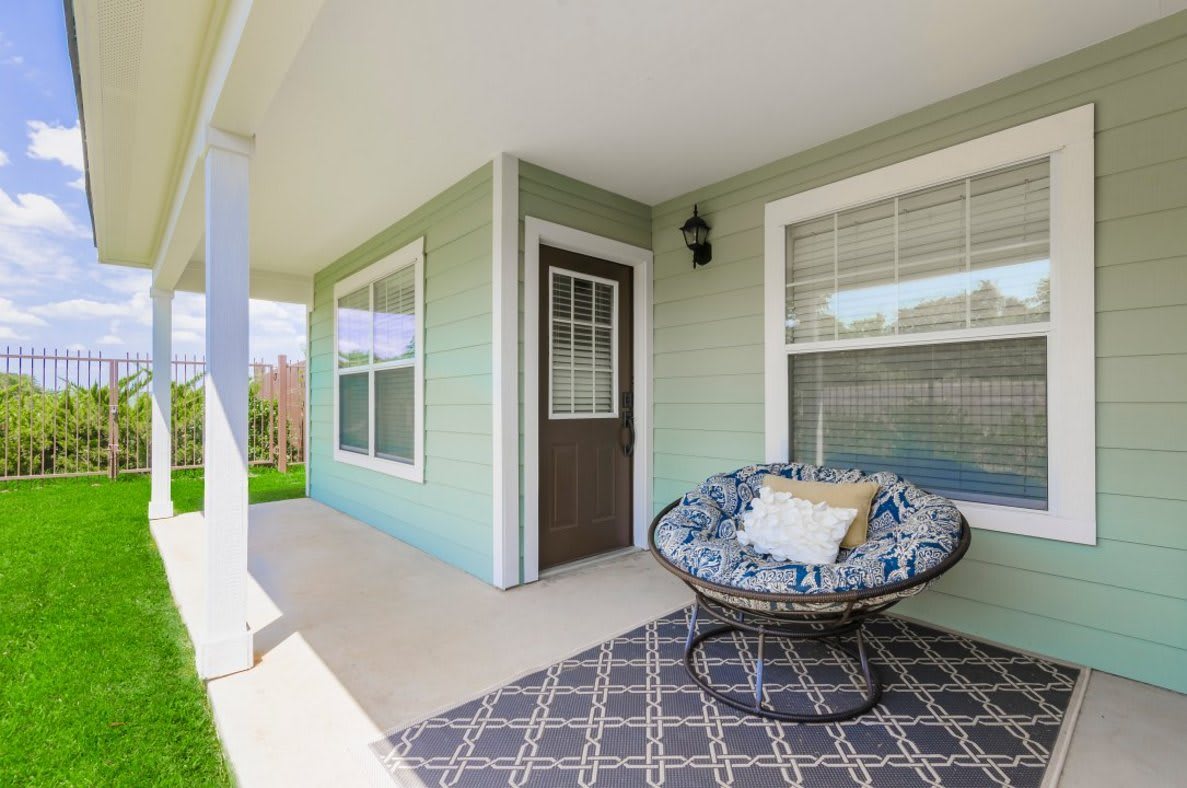 A cozy front porch with a comfortable chair and decorative rug.