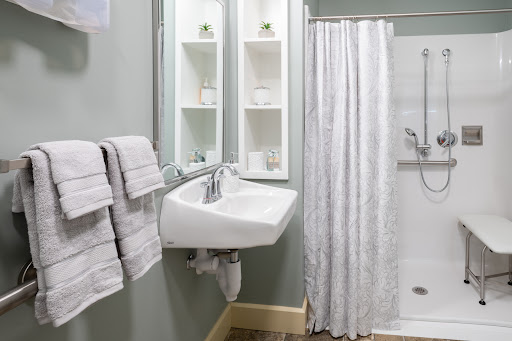 A modern bathroom featuring a sleek sink, a shower curtain, neatly arranged towels, and stylish storage.