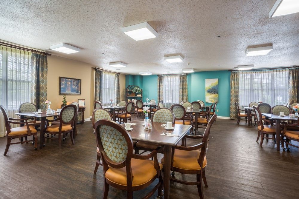 A well-lit dining room with neatly arranged tables and chairs, featuring elegant decor.