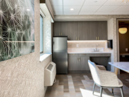 A modern kitchenette featuring sleek cabinets, a refrigerator, and comfortable seating.