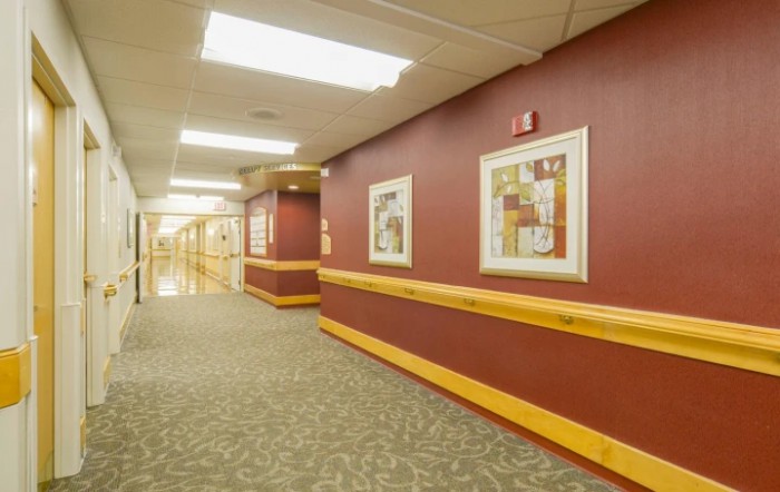 A well-lit hospital hallway featuring framed artwork on the walls.