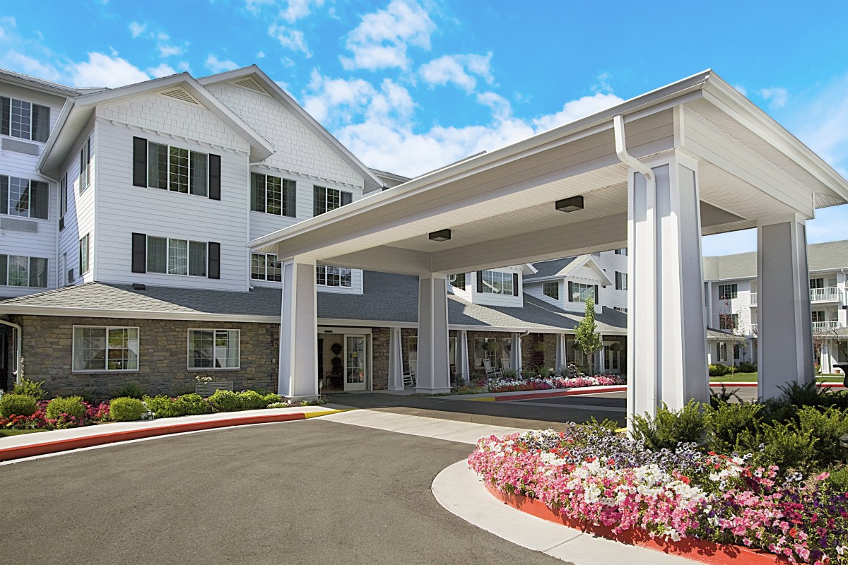 A large building with a covered entrance and landscaped driveway.