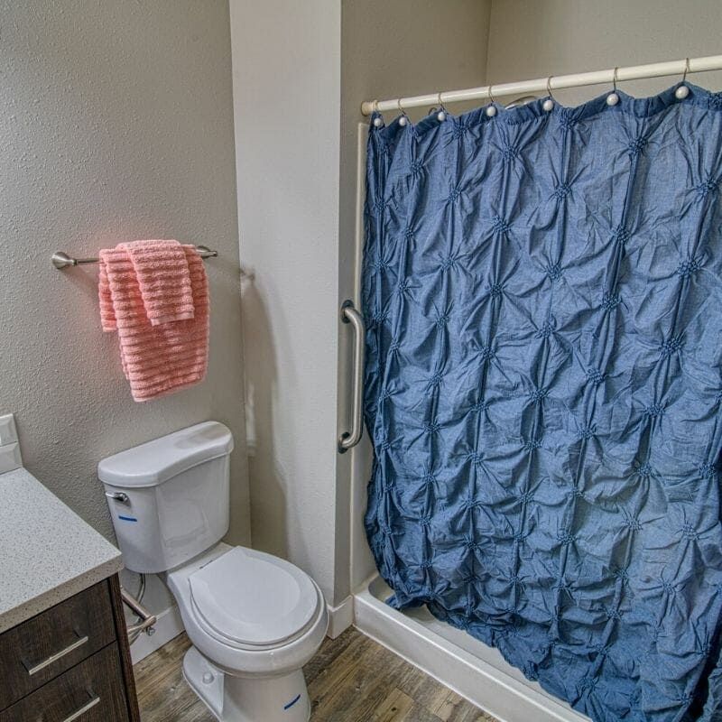 A compact bathroom featuring a toilet, sink, and blue shower curtain.