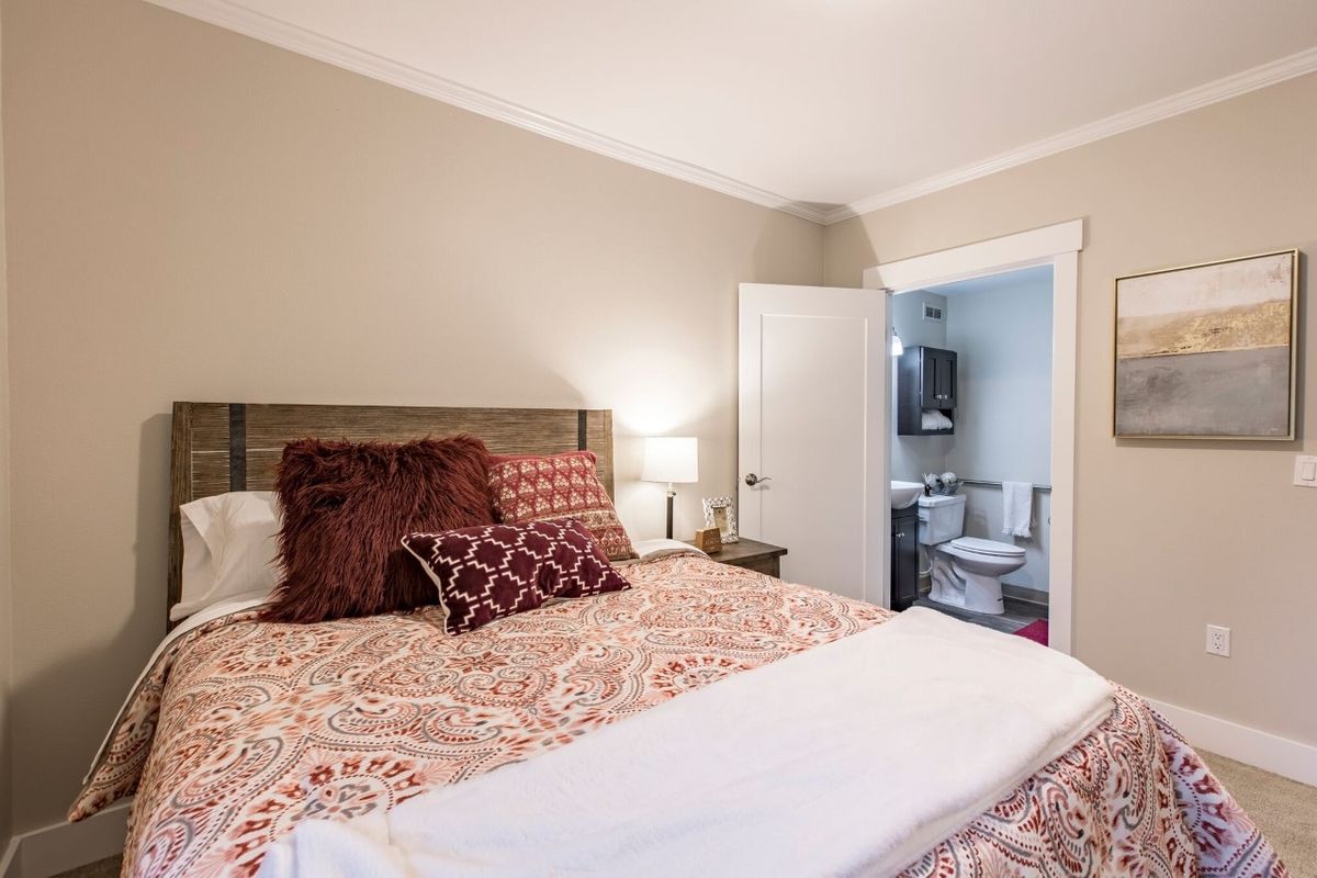 A cozy bedroom with decorative pillows and an adjacent bathroom.