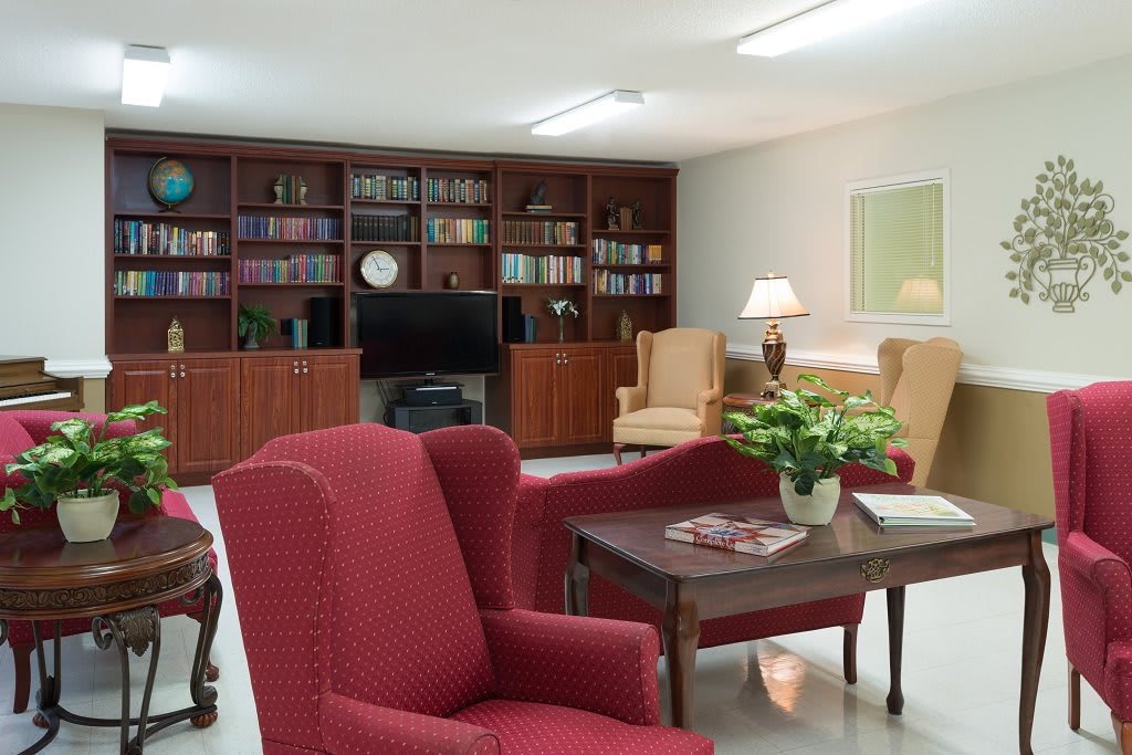 A cozy living room with red armchairs, a bookshelf, and a television.