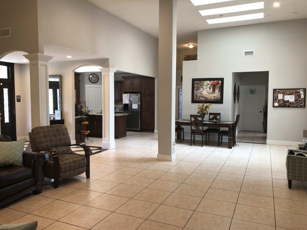 A spacious and modern living room with an open dining area, featuring tiled floors and ample natural light.