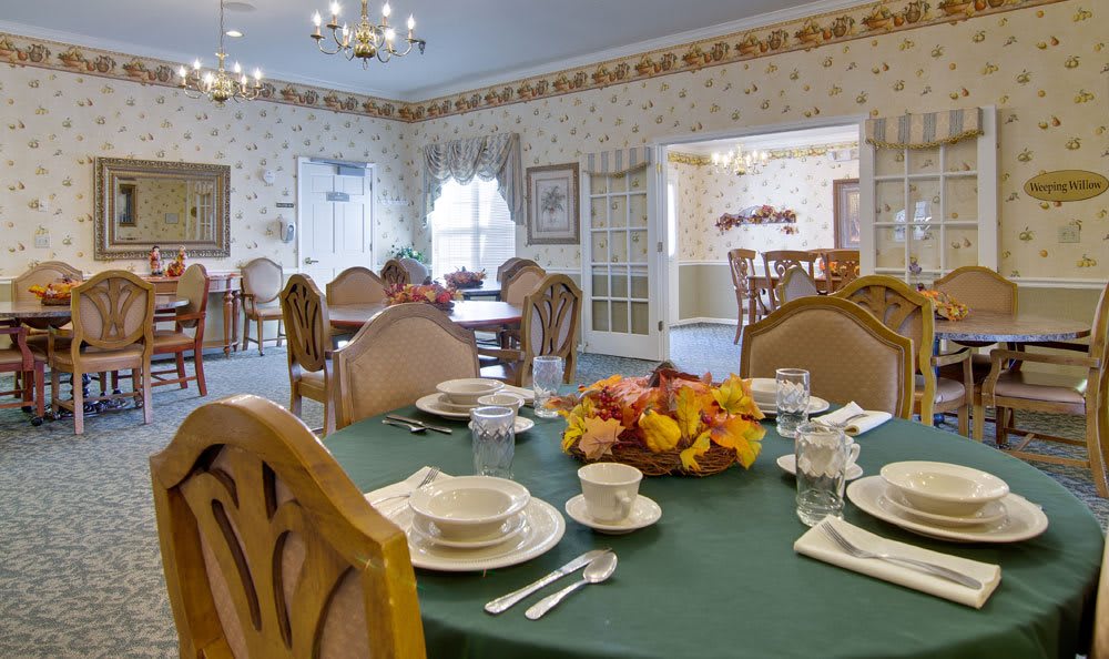A warmly decorated dining area with a table set for a meal, featuring an autumn-themed centerpiece.