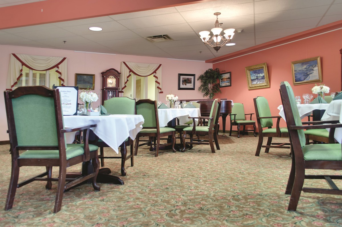 A cozy dining area with neatly arranged tables and chairs, adorned with elegant decor and a chandelier.