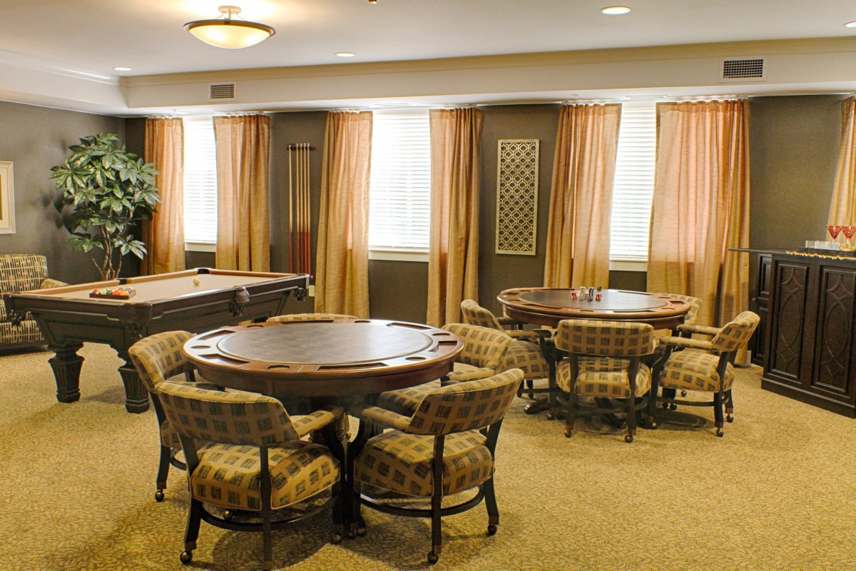 A well-furnished room featuring round tables and comfortable chairs, with elegant curtains lining the windows.