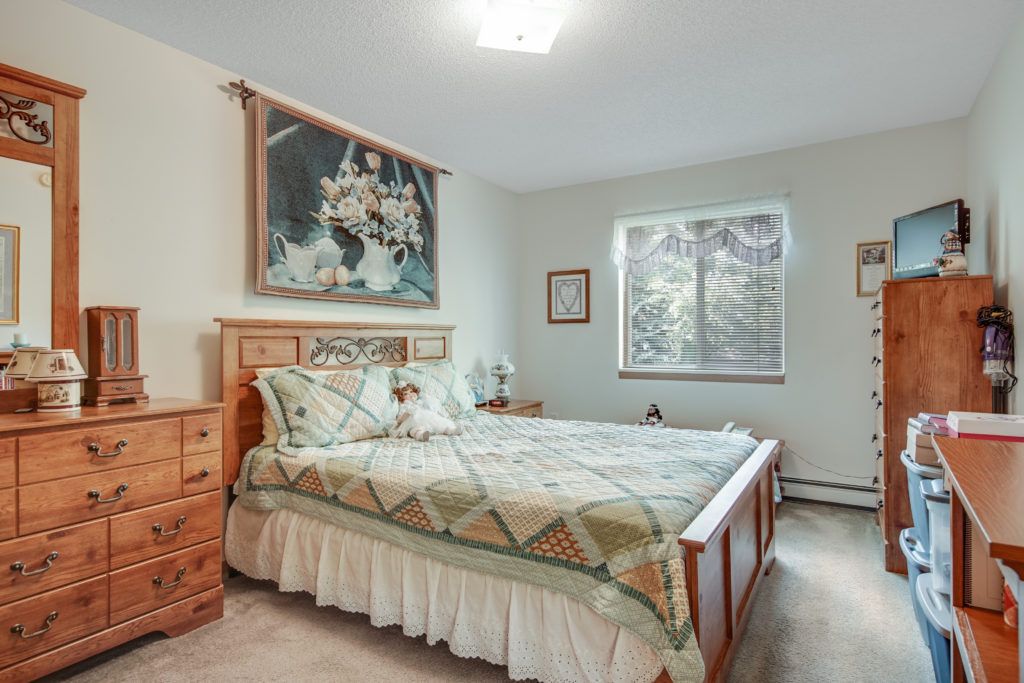 A cozy bedroom with a wooden bed frame, matching furniture, and wall decor.